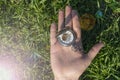 Vintage pocket watch in male hand on a background of green grass. Steampunk watch. The clock mechanism is partially visible