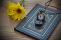 Vintage pocket watch and yellow flower lying on the old book Royalty Free Stock Photo