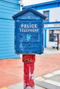 Vintage Police Telephone stand on red pole with blue box in front of shop Royalty Free Stock Photo