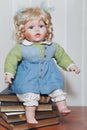 Vintage porcelain doll blonde sitting on stack of books Royalty Free Stock Photo