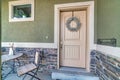 Vintage porch table and chair of house with front door decorated with wreath