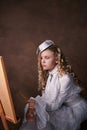 Vintage portrait of artist girl. child in white dress paints picture Royalty Free Stock Photo