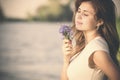 Vintage portrait of a beautiful young woman with a bouquet of wildflowers in hand on the banks of the river in the morning Royalty Free Stock Photo