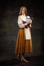 Vintage portrait of young adorable redhead girl in image of medieval person in renaissance style dress on dark
