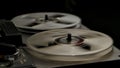 Vintage professional analog reel to reel tape recorder on black studio background. Transparent rotating coils reproduce