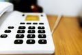 Vintage push-button white phone with black buttons on the table, blur