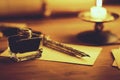 Vintage quill pen and inkwell on wooden table in candlelight Royalty Free Stock Photo
