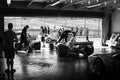 Black and White Photo of Vintage Race Cars In a Pitstop Garage.
