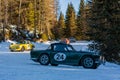 Vintage racing car driving classic rally on snow covert road