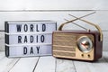 Vintage radio on white surface with World Radio Day lightbox, nostalgic charm
