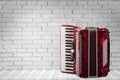 Vintage red accordion on brick wall background