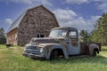 Vintage red barn with abandoned pickup truck in a farmyard on the prairies in Saskatchewan Royalty Free Stock Photo