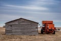 Vintage red combine abandoned beside an old barn in Saskatchewan, Canada