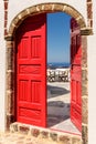 Vintage red door ajar and ocean view in Santorini, Greece. Royalty Free Stock Photo