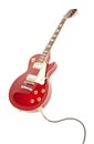 Vintage red electric solid body guitar plugged in.