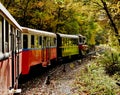 vintage red and green miniature nostalgy train passing through forest trail. retro style locomotive and carriages Royalty Free Stock Photo