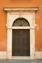 A vintage red house with old dark door. Ancient wooden door in old building wall. Facade of an old building with big Royalty Free Stock Photo