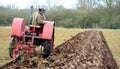 Vintage red International 1930`s tractor ploughing field. Royalty Free Stock Photo