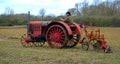Vintage red International 1930`s tractor ploughing field. Royalty Free Stock Photo
