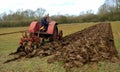 Vintage red International 1930`s tractor ploughing field. Royalty Free Stock Photo