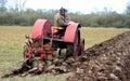 Vintage red International 1930`s tractor ploughing field. Royalty Free Stock Photo