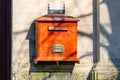 Vintage red mailbox on stone wall with shadow play Royalty Free Stock Photo
