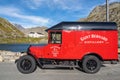 Vintage red van near a body of water surrounded by mountains Royalty Free Stock Photo