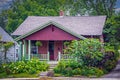 Vintage red wood shingled house with green trim and porch swing and landscaping including hydrangeas