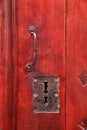 Vintage red wooden door with metallic handle and keyholes Royalty Free Stock Photo