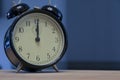 Vintage and retro analogue alarm clock indicating that it`s twelve o` clock, 12pm or 12am, on a dark blue background Royalty Free Stock Photo