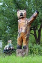 Vintage retro bear waving hello wooden sculpture next to small turtle sculpture on two cut down tree stumps surrounded with grass Royalty Free Stock Photo