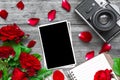 Vintage retro camera and blank photo frame with red rose flowers bouquet and lined notebook Royalty Free Stock Photo