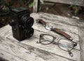 Vintage retro camera, eyeglasses and watch on wooden background