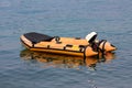 Vintage retro inflatable rubber boat with washed color and small outboard boat motor anchored in local harbour