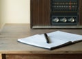 Vintage retro radio, notebook and pen on wooden table Royalty Free Stock Photo