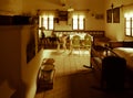 Vintage room with bed, cradle, furnace, table and chairs in old rural house. Sepia style image Royalty Free Stock Photo