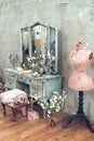 Vintage room in a photo studio with a vintage wooden dressing table with a big mirror, vases with flowers, a pink mannequin