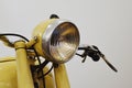 Vintage round headlight and steering handlebar on czechoslovak motorcycle from fifties of 20th century, yellow colour