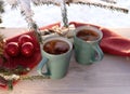 Vintage rustic card with green porcelain cups of tea on white wooden table decorated with snowy fir tree and red Royalty Free Stock Photo