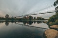 Vintage rustic suspension bridge over river in autumn. River crossing concept. Royalty Free Stock Photo