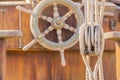 Vintage sailboat deck with old wooden helm wheel and nautical pulley with ropes