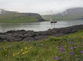 Vintage sailing ship in front of the high Hornbjarg cliffs hiden in fog at Hornstrandir national park, Iceland, purple and yellow Royalty Free Stock Photo