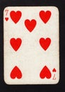 A vintage seven of hearts playing card on a black background.