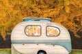 Vintage seventies white caravan with flower curtains in front of