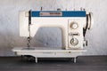 Vintage sewing machine from 60s or 70s on wooden table with white wall background Royalty Free Stock Photo