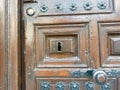 Vintage shabby wooden door of dark brown colour with keyhole and decorative metallic details. Rustic antique entrance