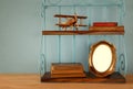 Vintage shelf with old wooden plane toy, books and blank photo frame Royalty Free Stock Photo