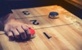 Vintage shuffle board game with red and blue disc and hand holding red blue disc on wooden shuffle table. Shuffleboard table game Royalty Free Stock Photo