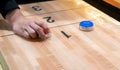 Vintage shuffle board game with red and blue disc and hand holding red blue disc on wooden shuffle table. Shuffleboard table game Royalty Free Stock Photo