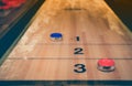 Vintage shuffle board game with red and blue disc on wooden shuffle table. Shuffleboard table game with selective focus. Royalty Free Stock Photo